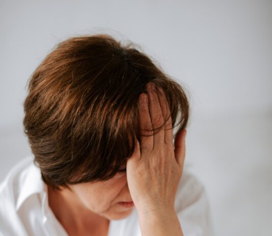 갱년기 증상 완화와 호르몬 건강 지키는 방법 a woman sitting on a bed holding her head in her hands