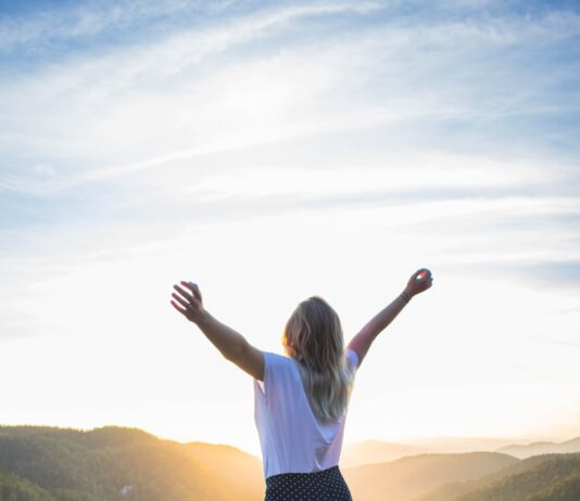 웰니스 문화, ‘나’를 돌보는 새로운 라이프스타일로 떠오르다 woman in white shirt and black pants standing on rocky mountain during daytime
