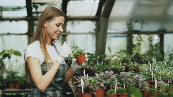 Photo by Vitaly Gariev Woman tending to potted plants in a greenhouse
